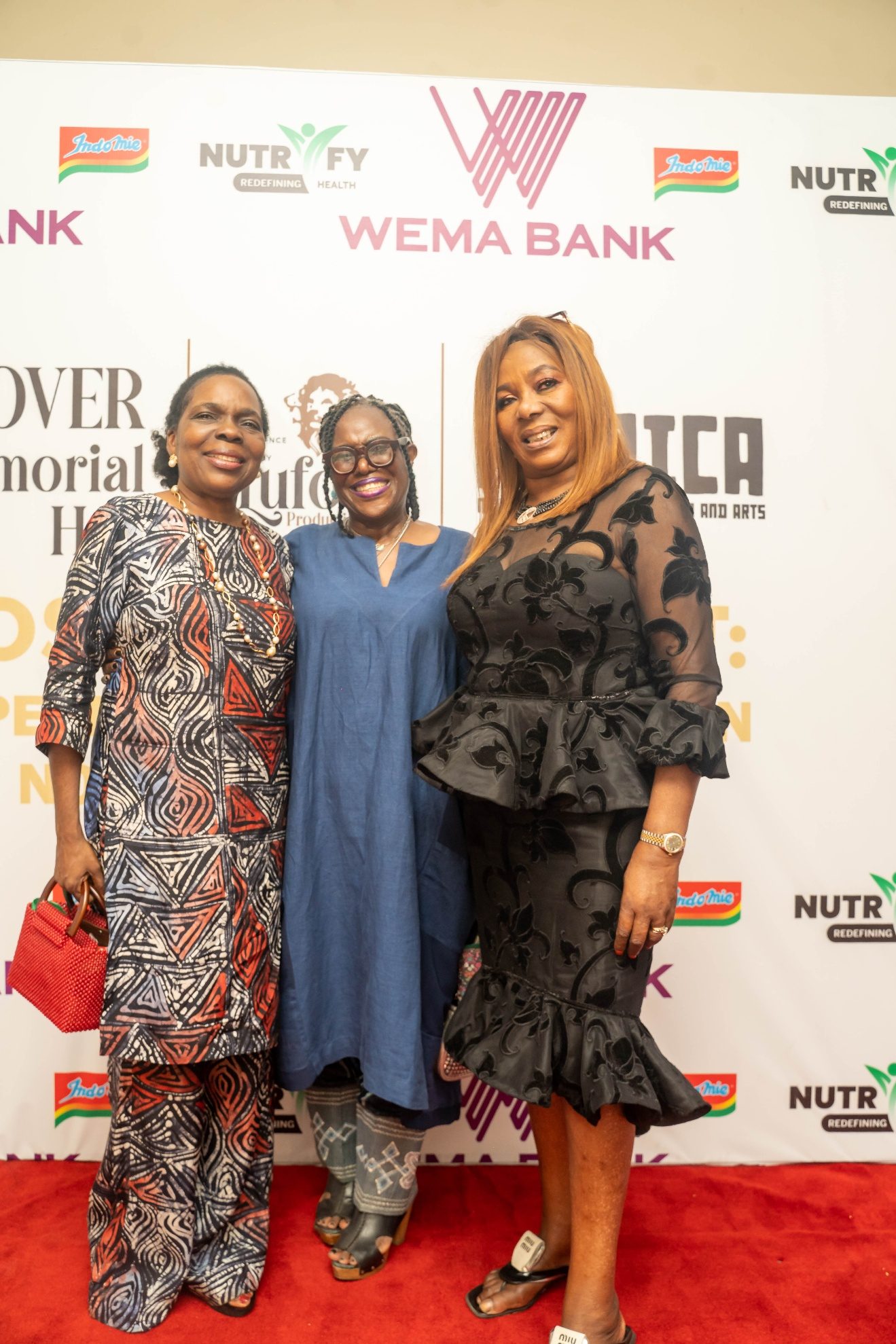 Three guests photographed together on the red carpet in front of the exhibition backdrop.