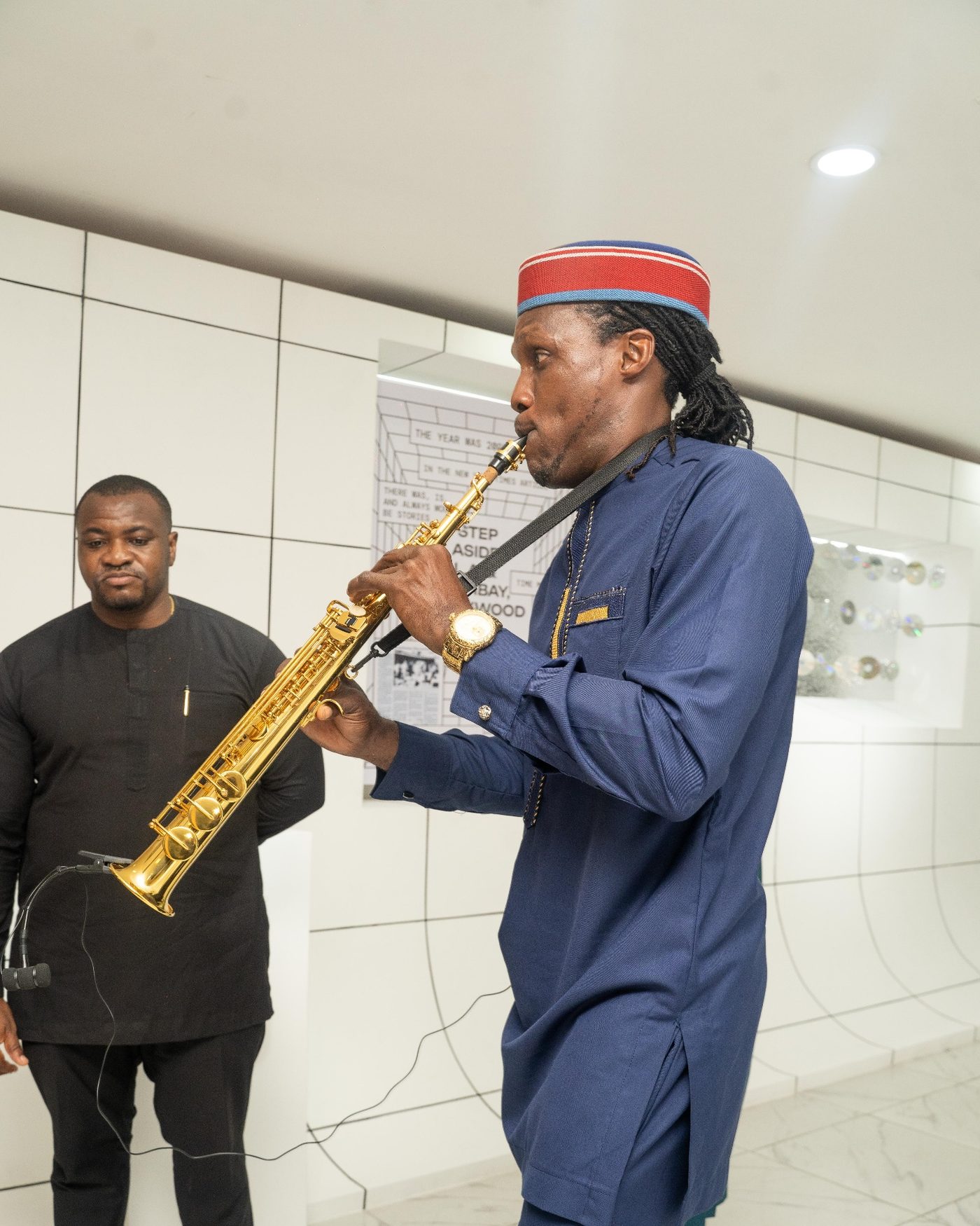 A saxophonist performing in the gallery at the opening, a second musician standing behind him.